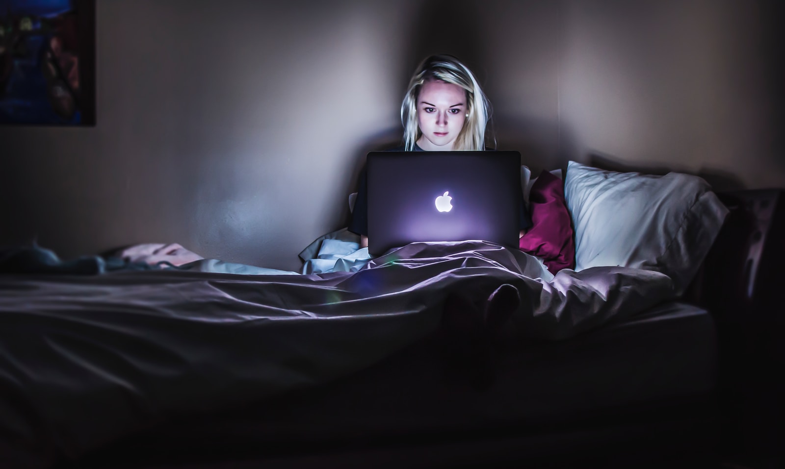 woman sitting on bed with MacBook on lap